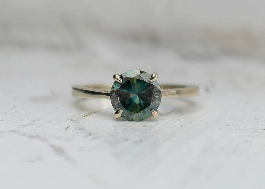 Commissioned gold ring featuring moissanite stone on light background