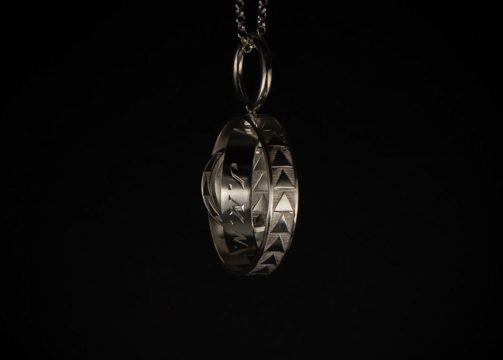 Remodelled pendant made from a baby bangle preserving original engravings on black background
