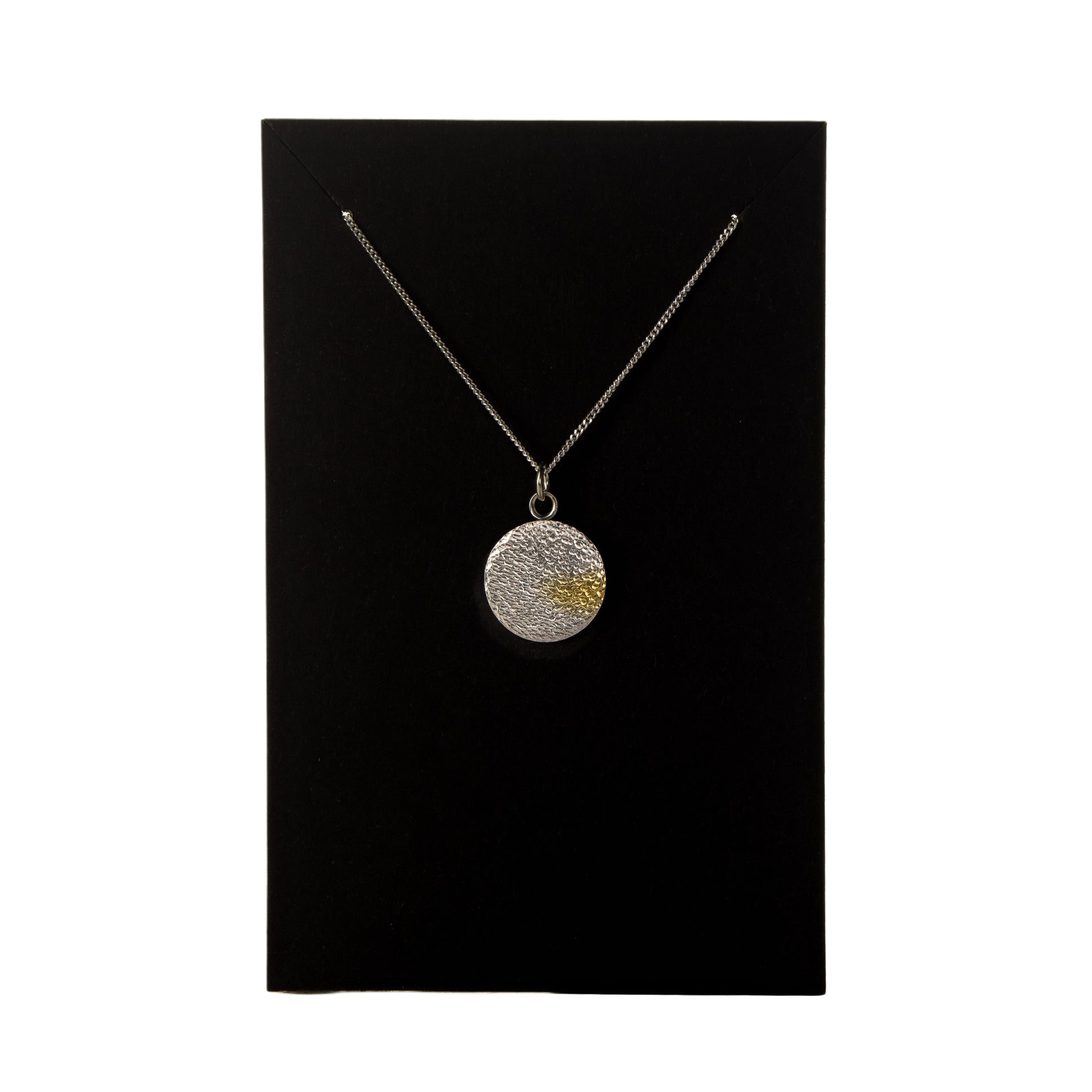 Hammered silver disc necklace with gold detail shown on black jewellery card