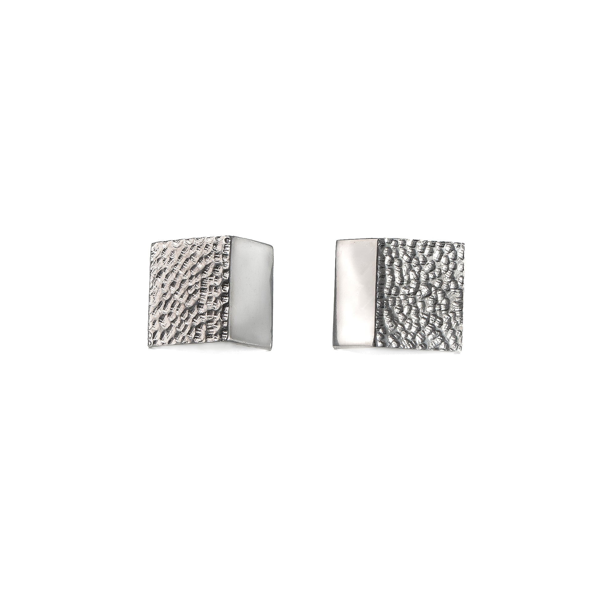 Rectangular silver stud earrings with a hand carved texture on a white background