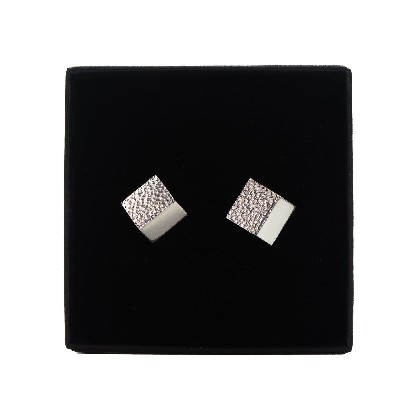 Fold-formed rectangular silver stud earrings showing textured surface and polished edge