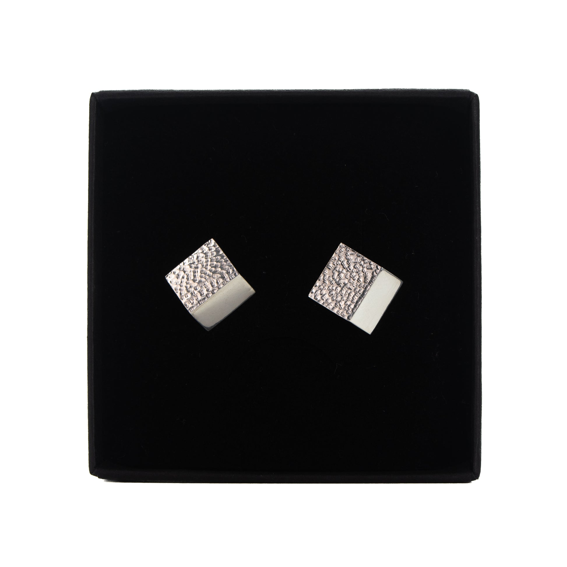 Fold-formed rectangular silver stud earrings showing textured surface and polished edge