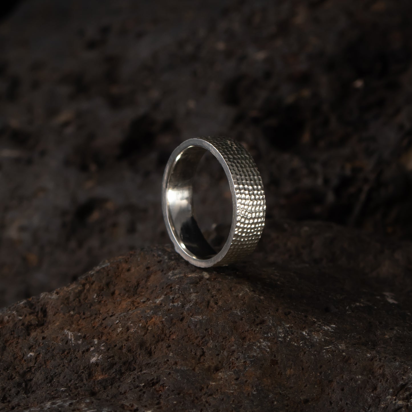 Textured silver band ring in sterling silver with a hand-carved surface on stone background