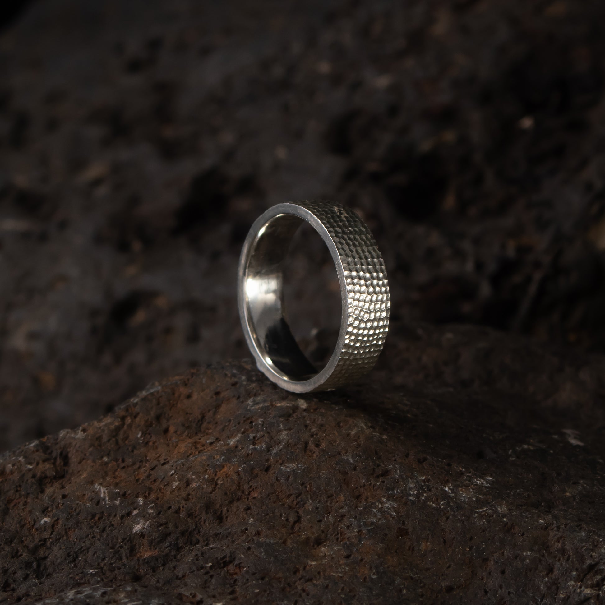 Textured silver band ring in sterling silver with a hand-carved surface on stone background