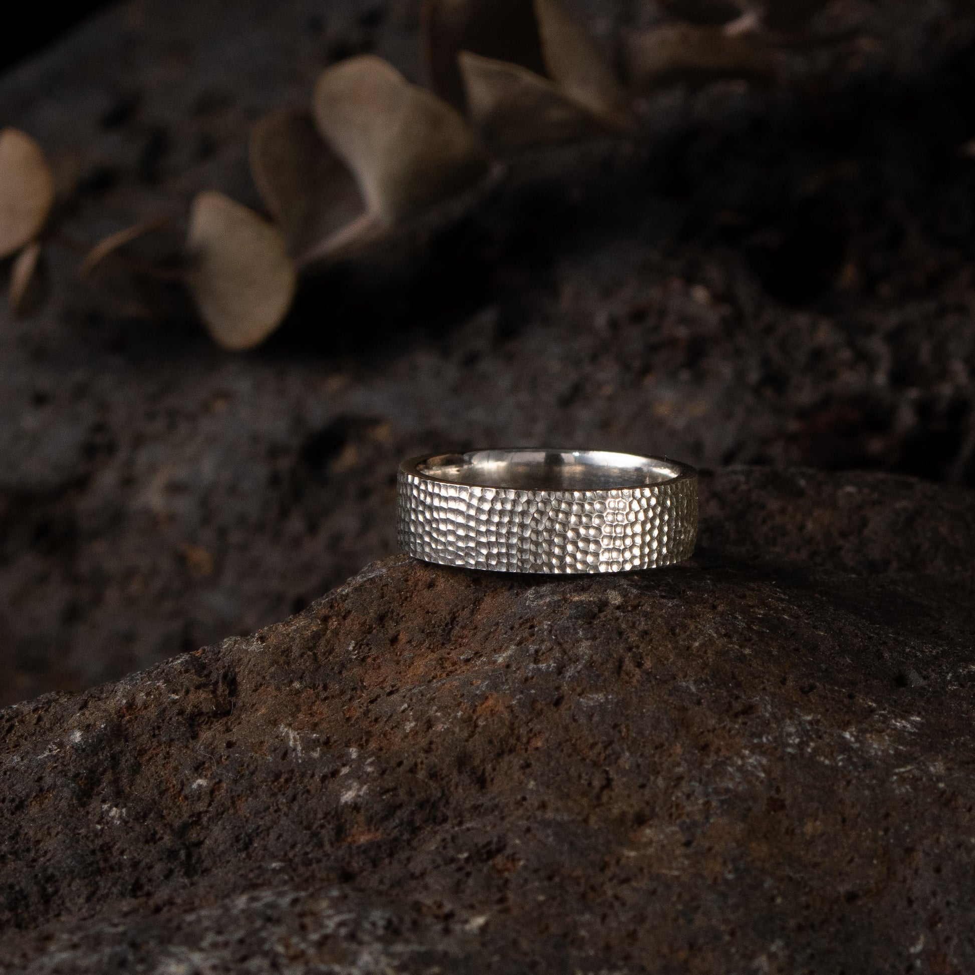 Textured silver band ring in sterling silver with a hand-carved surface on styled background